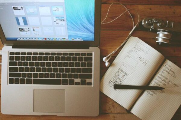 Laptop con quaderno, penna e fotocamera