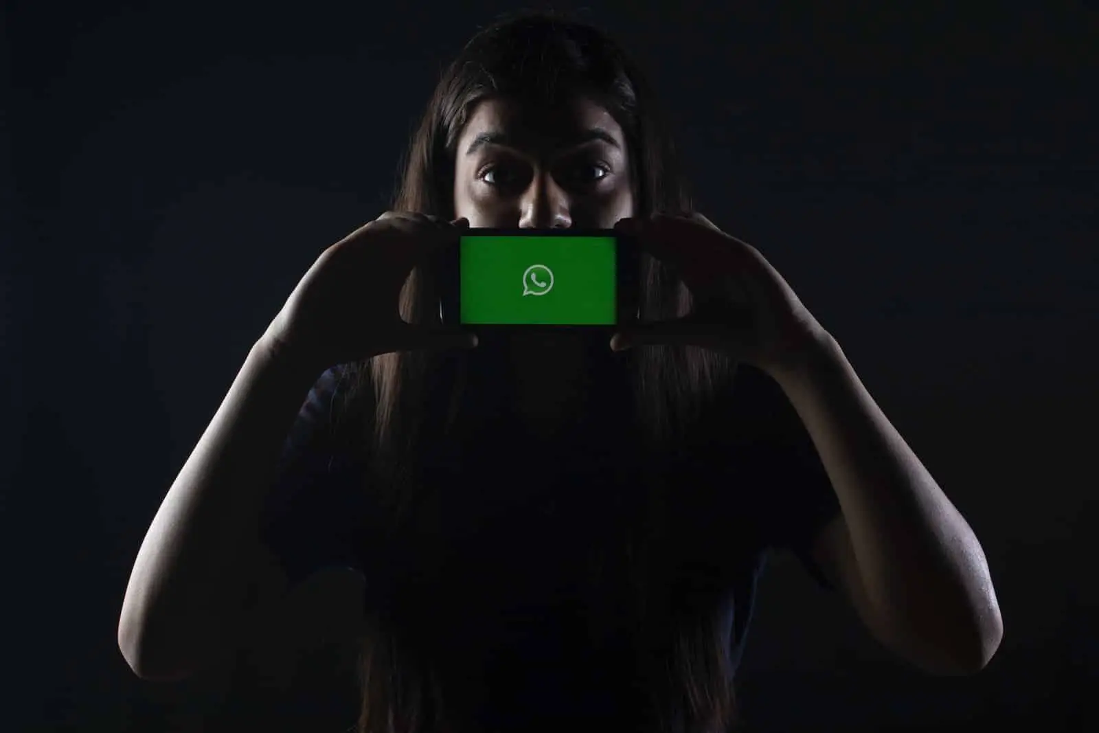 femme tenant un smartphone noir avec le logo Whatsapp